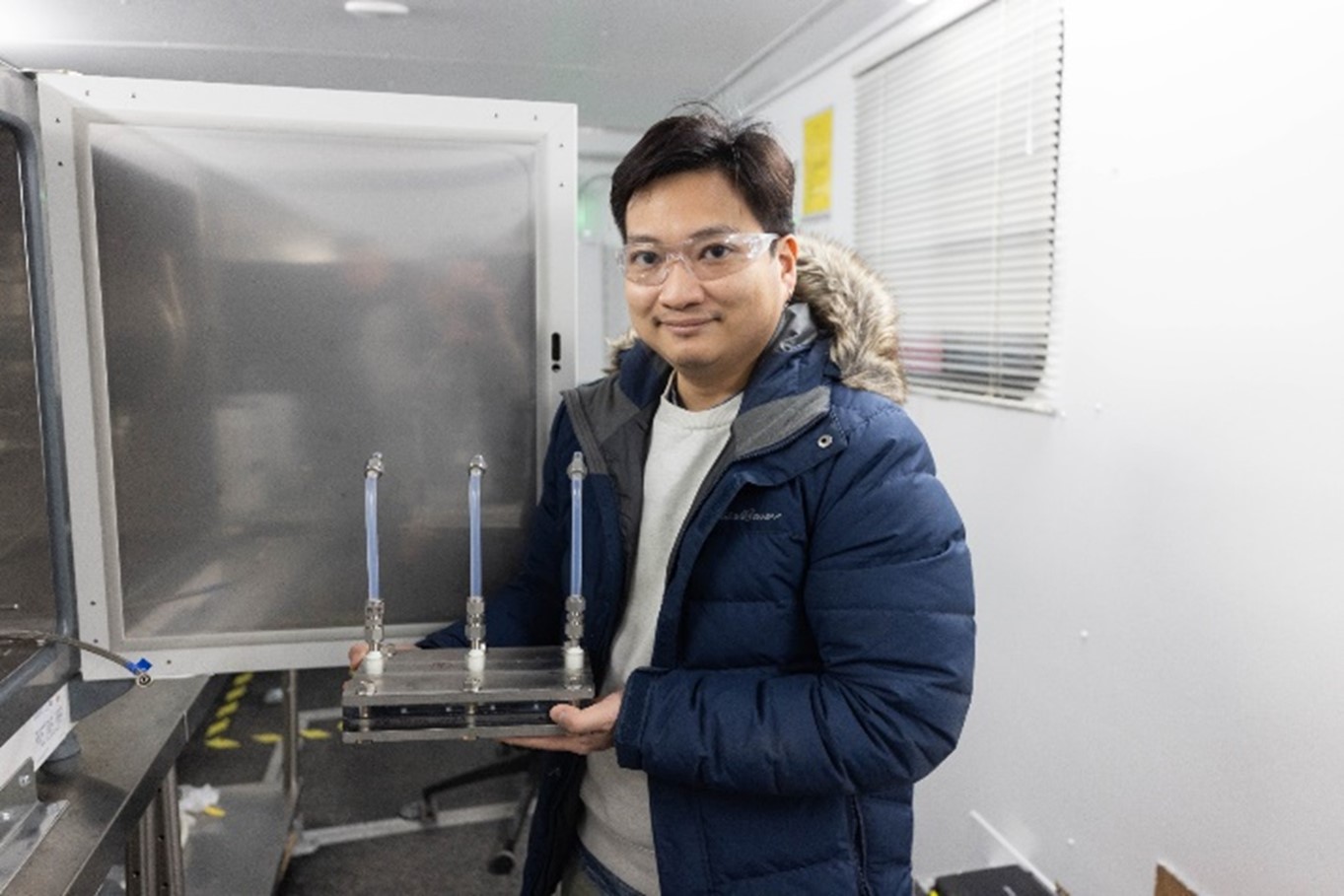 James Tran holding a membrane module inside NETL’s U.S. Steel trailer.