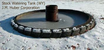 View of a standard watering tank. Produced water flows from the central pipe to fill the small impoundment.