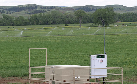 CBNG wellhead equipped with radio monitoring system and field irrigation in background in Wyoming's Powder River Basin.