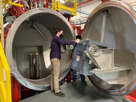 A photo of two men working on NETL’s 500lb Vacuum Induction Melting Reactor