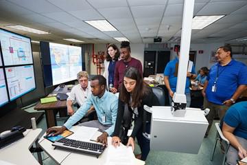 Several people standing around a computer.