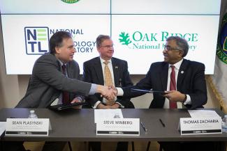 Assistant Secretary for Fossil Energy Steve Winberg looks on as Acting NETL Director Sean Plasynski (left) and ORNL Director Thomas Zacharia shake hands.