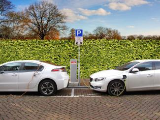 Two white sedans parked at an electric car charging station.