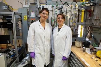 Caption: Former Mickey Leland Intern Yuniba Yagues (left) is seen here with her mentor NETL Researcher Christina Wildfire standing in front of NETL’s Variable Frequency Microwave Reactor. NETL’s innovations in microwave reaction science were key to a successful partnership that led to an improved ammonia production process.